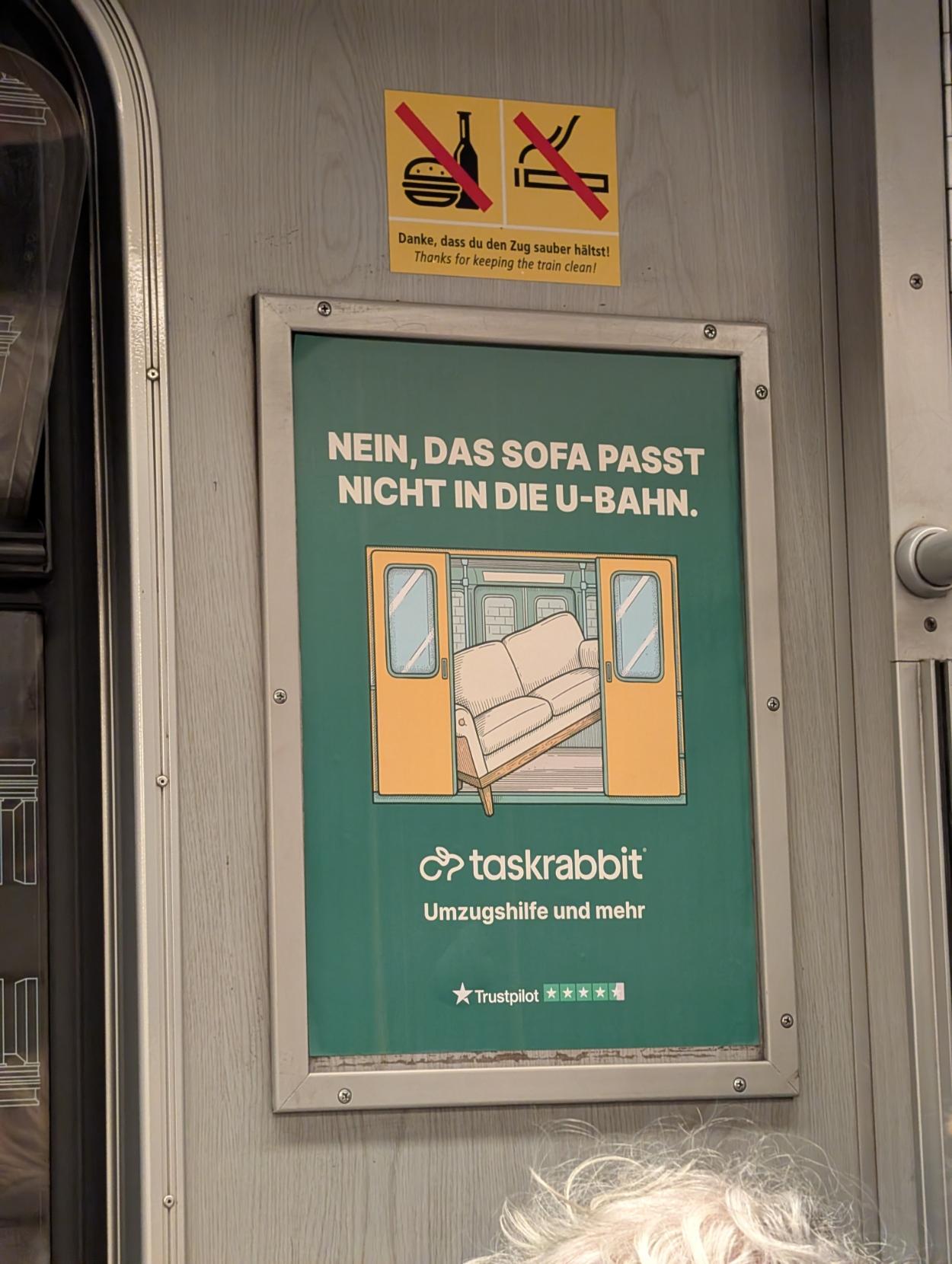 A taskrabbit ad inside U-Bahn train, it says "nein, das Sofa passt nicht in die U-Bahn" and shoes a sofa stuck inside U-Bahn carriage and preventing doors from closing